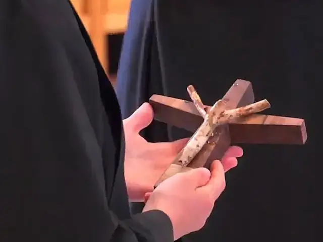Hands holding small wooden cross